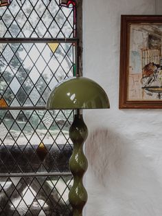 a green lamp sitting on top of a table next to a window