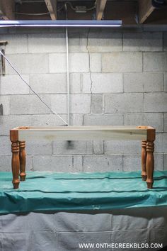 a table with a surfboard on it in front of a brick wall and blue tarp