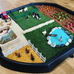 a toy farm with animals in it on a wooden floor next to some fake grass