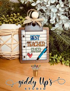 a wooden sign that says best teacher ever with a pen and pencil next to it