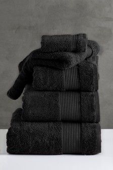 black towels stacked on top of each other in front of a gray wall and floor