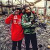 two men standing next to each other in the middle of a room filled with debris