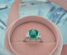 This Elegant Platinum three stone ring has a Natural Cushion Cut Colombian Emerald from the Top Muzo Mine with a GIA Certificate. The side stones are Natural Brilliant Cut Trapezoid Pair of Matching Diamonds. GIA#5202111099 3.34 Carat Cushion Modified 9.64x8.93x5.64 with moderate F2 clarity enchancement. 2 Matching Trapezoid Brilliant Cut Diamonds weigh 0.71 carats total weight and are graded G in color and SI1 to SI2 in clarity. Platinum weight is 5.14 DWT. Ring can be sized. Luxury Dazzling Emerald Ring With Accent Stones, Luxury Princess Cut Emerald Ring With Accent Stones, Luxury Three Stone Emerald Ring Gift, Three Stone Cushion Cut Ring, Fine Jewelry Emerald Platinum Ring With Three Stones, Platinum Three Stone Emerald Ring, Luxury Three Stone Emerald Wedding Ring, Luxury Three Stone Emerald Ring For Wedding, Three-stone Emerald Diamond Ring As Gift