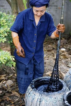 a woman in blue shirt and black pants holding a metal pipe with water coming out of it