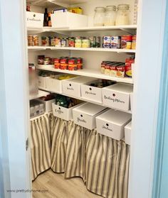 an organized pantry with white bins, striped curtains and pull out shelve