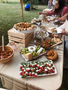 a table full of food with people sitting at the tables eating and talking to each other