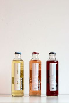 three different types of soda bottles lined up on a shelf in front of a white wall