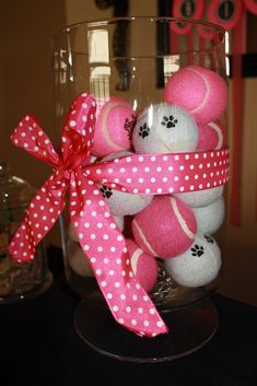 a glass vase filled with lots of pink and white stuffed animals on top of a table