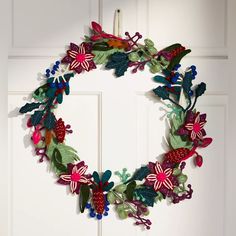 a christmas wreath hanging on the front door with holly berries and candy canes attached to it