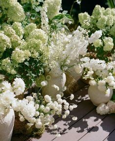 several white vases filled with flowers on a wooden table