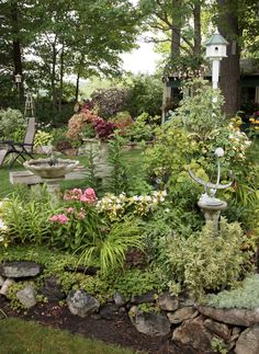 a garden filled with lots of different types of flowers and plants next to a tree