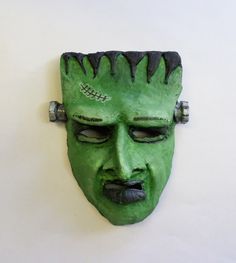 a green mask is hanging on the wall