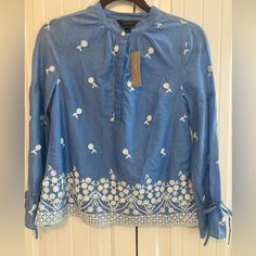 This J. Crew Pxxs Blue Floral Embroidered Popover Henley Top Is Perfect For Travel And Casual Occasions. The Long-Sleeved Blouse Has A Flared Tie Cuff And A Button Closure. The Boho Peasant Top Is Made Of 100% Cotton And Is Lightweight. It Features A Beautiful Floral Pattern And Is Perfect For Petites. The Top Is Not Handmade And Is Not Vintage. The J. Crew Brand Is Known For Its Quality And Style, Making This Top A Great Addition To Your Wardrobe. Light Blue Embroidered Tops For Spring, Spring Embroidered Blue Tops, Blue Embroidered Spring Tops, Blue Embroidered Relaxed Fit Blouse, Blue Embroidered Tops For Spring, Spring Blue Embroidered Top With Embroidered Hem, Spring Blue Embroidered Top With Hem Detail, Blue Floral Print Embroidered Top, Blue Embroidered Top With Hem For Spring