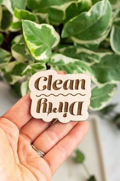 a person holding up a wooden sign that says clean and happy in front of some plants