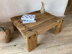 a wooden table sitting on top of a hard wood floor next to a potted plant