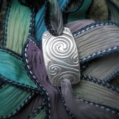 This bracelet features a beautifully detailed swirling Celtic spirals pattern that is found on many ancient artifacts and monuments. This piece measures approx. 26-27mm in length. (shown with jewel colored ribbon) ~~If you would like to purchase extra ribbons for your bracelet, they cost $6.50 each. Please message me and I will be happy to make a custom listing for you.~~ ~Silver & Silk~ wrap bracelets are made with 99.9% pure, hand-formed, recycled, eco-friendly silver. The silk ribbons are Handmade Spiral Bohemian Bracelets, Handmade Bohemian Spiral Bracelets, Handmade Bohemian Spiral Bracelet, Handmade Bohemian Swirl Jewelry, Artistic Handmade Swirl Jewelry, Silk Wrap Bracelets, Celtic Spiral, Jewel Colors, Ribbon Wrap