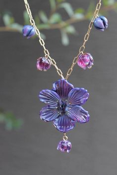 a purple flower is hanging from a gold chain