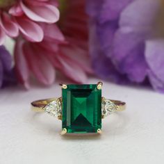 This handmade emerald ring is a true work of art, featuring a stunning octagon cut emerald gemstone that is beautifully complemented by two trillion-shaped moissanites (or simulated diamonds, depending on the metal). The emerald's deep green hue is breathtaking, and its octagon cut adds a unique and eye-catching dimension to the ring. The moissanites (or simulated diamonds) set on either side of the emerald add just the right amount of sparkle, creating a truly mesmerizing piece of jewelry. Insp Rectangle Emerald Ring, Ring Rectangle, Rectangle Ring, Green Ring, Green Rings, May Birthstone, Knot Ring, Wire Wrapped Rings, Emerald Engagement Ring