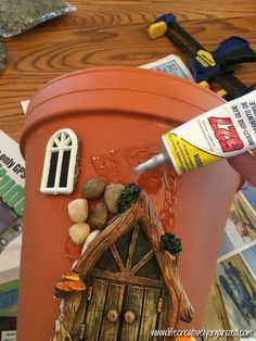 a red bucket filled with rocks and paint next to a wooden table topped with magazines