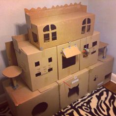 several cardboard boxes stacked on top of each other with cats in the windows and cat houses