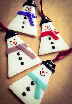 four snowman ornaments hanging from a red ribbon