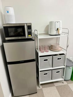 a microwave oven sitting on top of a shelf next to a silver refrigerator freezer