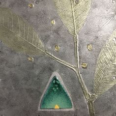 a close up of a metal plate with leaves on it and a green triangle in the middle