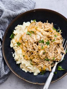 a black plate topped with mashed potatoes and shredded chicken