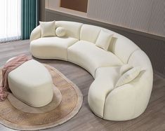 a large white couch sitting on top of a wooden floor next to a round rug