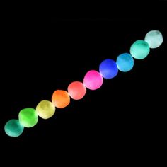 a long line of glowing balls on a black background with the colors of the rainbow