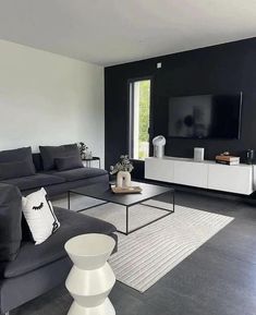 a black and white living room with modern furniture in the corner, large window to the right