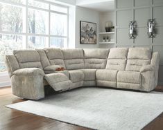 a living room with a large sectional couch and white rug in front of the window