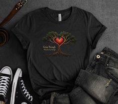 Embrace the power of transformation with our 'Grow Through What You Go Through' Inspirational Quote T-Shirt, featuring a surreal image of a tree with roots intertwined around a glowing heart. This design symbolizes the resilience and strength that comes from overcoming challenges, with the phrase 'Grow Through What You Go Through' reminding you that growth often arises from adversity. Perfect for those who value inspiration, motivation, and mental health awareness, this tee is both powerful and thought-provoking. Crafted from premium Bella + Canvas 3001 fabric, this t-shirt offers a soft, comfortable fit, ideal for moments of reflection or sharing a message of resilience. Whether you're navigating personal challenges or supporting someone else's journey, this shirt is a beautiful expressio Tree With Roots, Glowing Heart, Message T Shirts, Overcoming Challenges, Health Awareness, Mental Health Awareness, Tree Art, Inspirational Quote, Favorite Things Gift