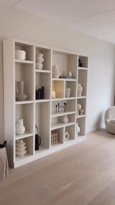 an empty room with white shelves filled with vases