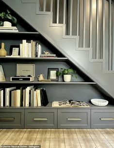 a bookshelf with many books on it under the stairs