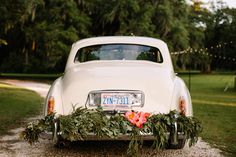 an old white car is decorated with greenery and flowers