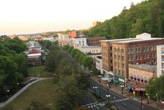 an aerial view of a city street with buildings on both sides and trees in the foreground