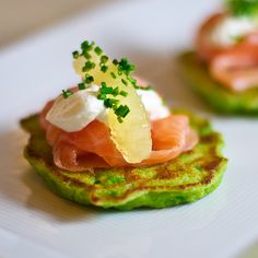 small appetizers are arranged on a plate with green garnish and sour cream