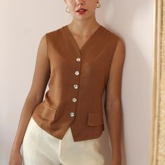 Vintage handmade statement vest blouse in a chocolate brown shade. V neckline and delicate flower-shaped mother of pearl button up fastening. Tailored fit with a slightly cinched waistline to hug beautiful your figure. Decorative front pockets. Lightweight and soft against the body.  You can wear it both as a blouse or layered with a top underneath. It's the perfect garment for a standout look from day to night! BRAND: No tag, handmade MATERIAL: No tag, estimated as viscose **CONDITION: Excellen Brown Vest With Button Closure For Work, Elegant Brown V-neck Blouse, Brown Buttoned Blouse For Work, Brown Blouse With Buttons For Workwear, Classic Brown Vest Top, Brown Summer Workwear Vest, Elegant Brown Workwear Vest, Elegant Brown Vest For Workwear, Brown V-neck Vest For Workwear