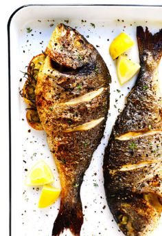 two fish on a plate with lemons and parsley