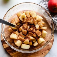 apples and cinnamon in a glass bowl on a cutting board