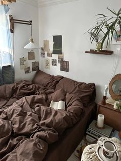 an unmade bed with brown sheets and pillows in a bedroom next to a window