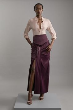 Experience Elevated Occasion Looks In Our Maxi Skirt, Which Features A Universally Flattering Flared Silhouette, A Comfortable High Waistline, And A Draped Design. The Thigh High Leg Split Makes A Statement, While The Draped Design Brings Dimension To The Piece. Style This Skirt With Anything, Like Block Heels And A T-Shirt For A Casual Daytime Look, Then With A Strappy Top And Sandals For A Holiday Outfit That Will Take You From Day To Night. Tailored Satin High Waisted Draped Maxi Skirt High Q Raw Silk Skirt And Top, Formal Pre-draped Flowy Skirt, Elegant Fitted Full Maxi Skirt, Formal Fitted Asymmetrical Maxi Skirt, Elegant Purple Maxi Skirt, Elegant Full Skirt For Daywear, Relaxed Fit Long Sleeve Evening Dress, Elegant Purple Dress With Full Skirt, Formal Asymmetrical Gathered Skirt