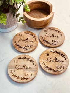 four wooden coasters with the names of family on them next to a potted plant