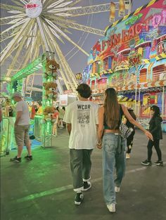 two people are walking in front of an amusement park