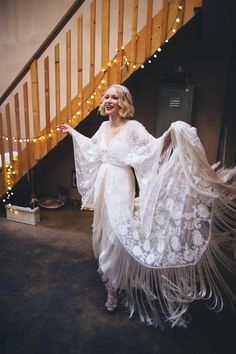 a woman in a white dress standing next to a stair case with lights on it