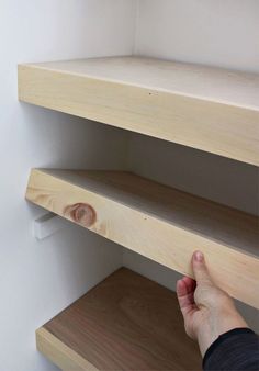 a person is reaching for the bottom shelf of a bookcase that's made out of plywood