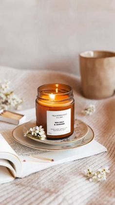 a candle sitting on top of a table next to a cup and saucer filled with flowers