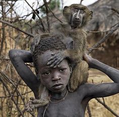 a monkey sitting on the back of a man's head in front of trees