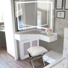 a white chair sitting in front of a vanity with a mirror on it's wall